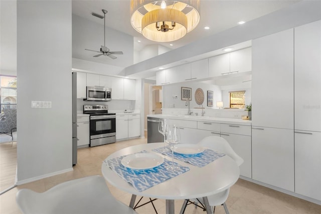 kitchen featuring appliances with stainless steel finishes, a towering ceiling, ceiling fan, sink, and white cabinetry