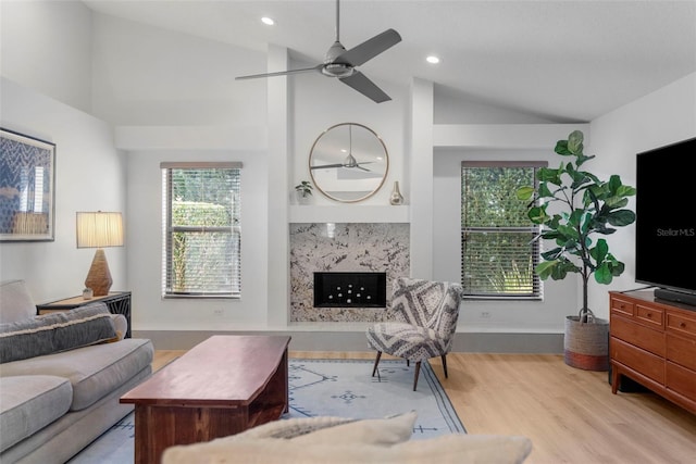 living room featuring light hardwood / wood-style flooring, ceiling fan, lofted ceiling, and a premium fireplace