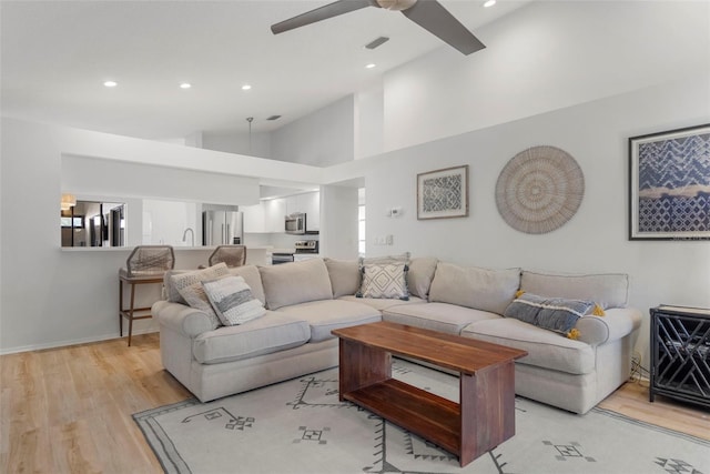 living room featuring ceiling fan, light hardwood / wood-style flooring, and high vaulted ceiling