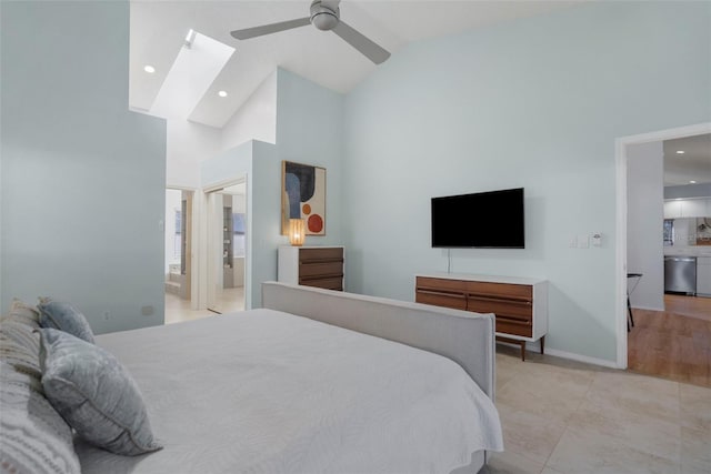 bedroom featuring a skylight, high vaulted ceiling, ensuite bath, and ceiling fan