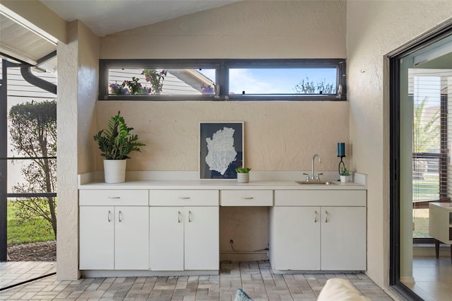 bathroom with a healthy amount of sunlight, sink, and vaulted ceiling