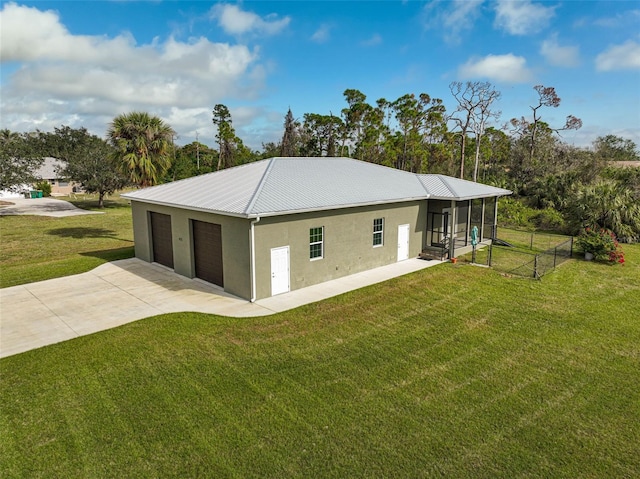 exterior space with a garage, a sunroom, and a lawn