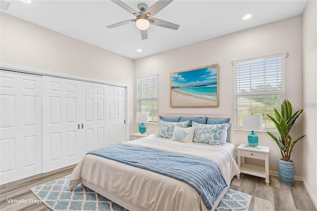 bedroom featuring ceiling fan, multiple windows, a closet, and light wood-type flooring