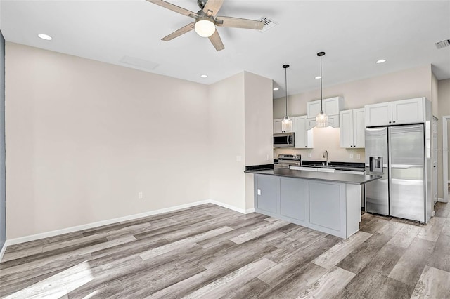 kitchen featuring decorative light fixtures, kitchen peninsula, white cabinetry, and stainless steel appliances