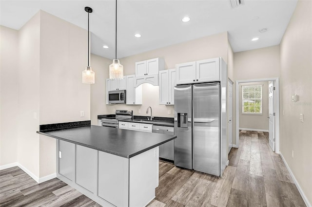 kitchen featuring light hardwood / wood-style floors, kitchen peninsula, appliances with stainless steel finishes, pendant lighting, and white cabinets