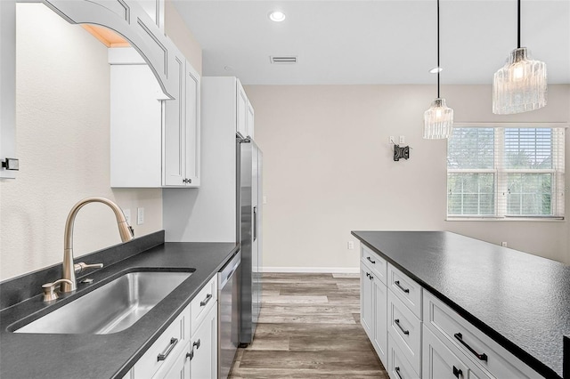 kitchen featuring dark hardwood / wood-style floors, pendant lighting, sink, white cabinetry, and stainless steel appliances