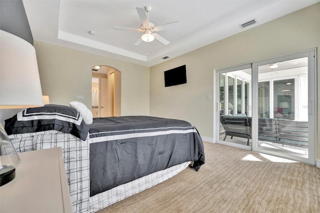 carpeted bedroom featuring access to outside, a raised ceiling, and ceiling fan