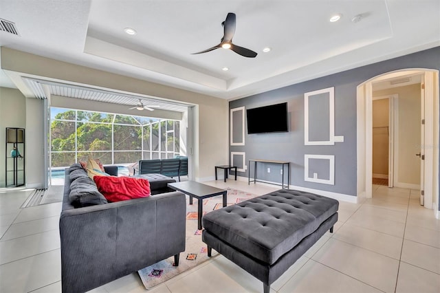 tiled living room with a raised ceiling and ceiling fan