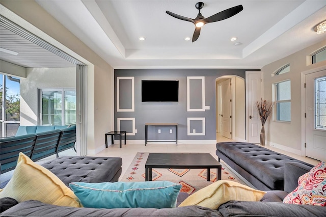 living room with a raised ceiling and ceiling fan