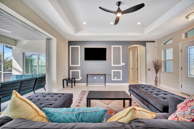 living room with a raised ceiling and ceiling fan