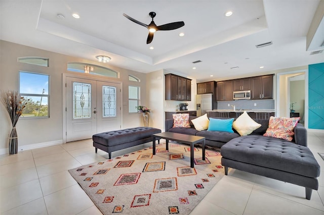 living room with ceiling fan, light tile patterned floors, and a tray ceiling