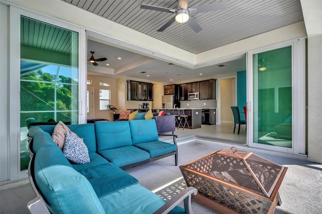 living room featuring ceiling fan and a raised ceiling