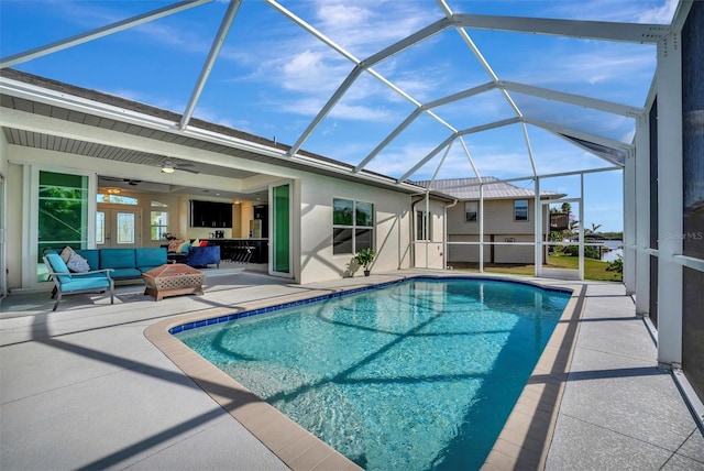 view of swimming pool featuring a patio area, ceiling fan, glass enclosure, and an outdoor hangout area