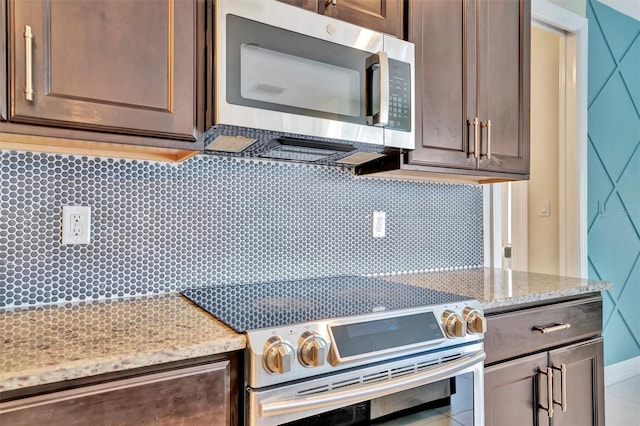 kitchen with dark brown cabinetry, light stone counters, and stove