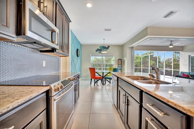 kitchen with decorative backsplash, appliances with stainless steel finishes, dark brown cabinetry, sink, and pendant lighting