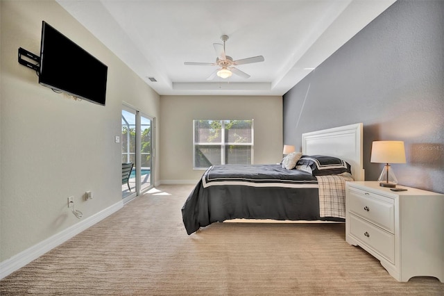 carpeted bedroom featuring access to outside, ceiling fan, and a tray ceiling