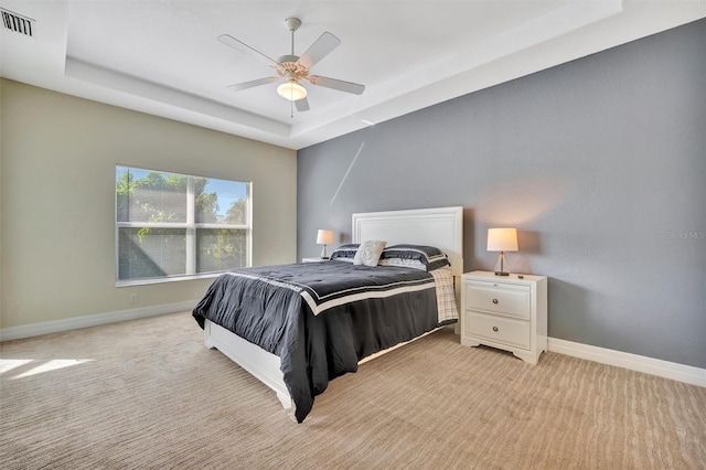 carpeted bedroom featuring a tray ceiling and ceiling fan