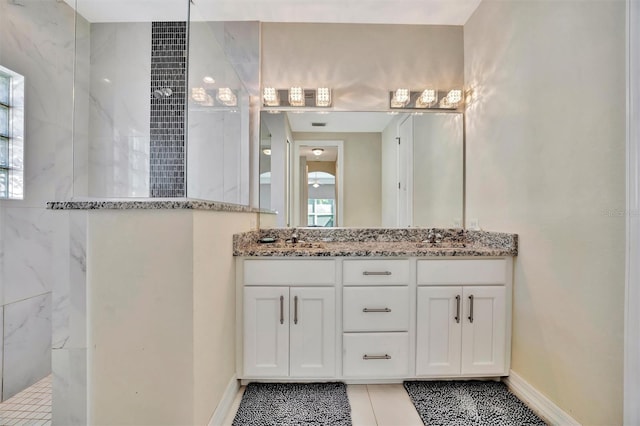 bathroom with tile patterned flooring, a tile shower, and vanity