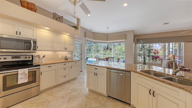 275 Royal Oak Way, Venice, FL 34292 - kitchen featuring stainless steel appliances, a ceiling fan, light tile patterned flooring, decorative backsplash, and light stone counters