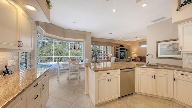 kitchen featuring pendant lighting, sink, stainless steel dishwasher, decorative backsplash, and light stone countertops