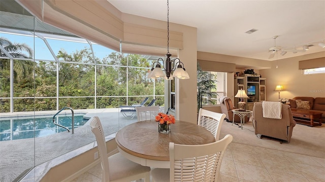 dining room with ceiling fan with notable chandelier, a healthy amount of sunlight, and light tile patterned floors