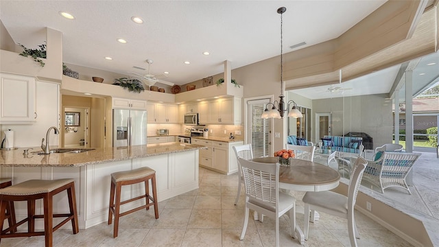 275 Royal Oak Way, Venice, FL 34292 - kitchen featuring appliances with stainless steel finishes, a ceiling fan, a peninsula, light stone counters, and backsplash