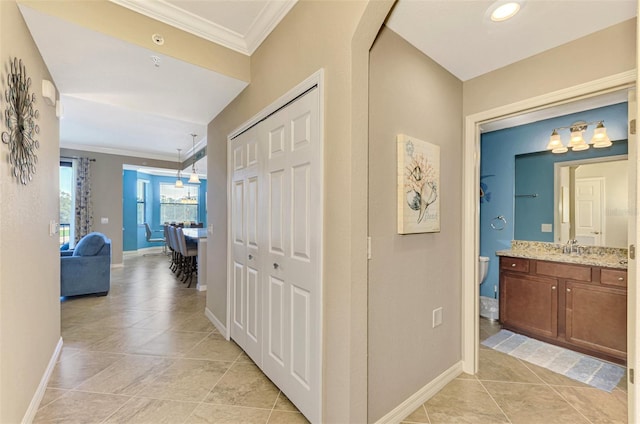 corridor with sink, light tile patterned floors, and ornamental molding