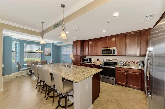 kitchen with sink, light stone countertops, an island with sink, decorative light fixtures, and stainless steel appliances