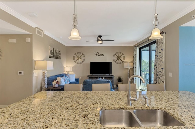 kitchen featuring light stone countertops, sink, ceiling fan, hanging light fixtures, and ornamental molding