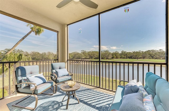 sunroom with ceiling fan and a water view