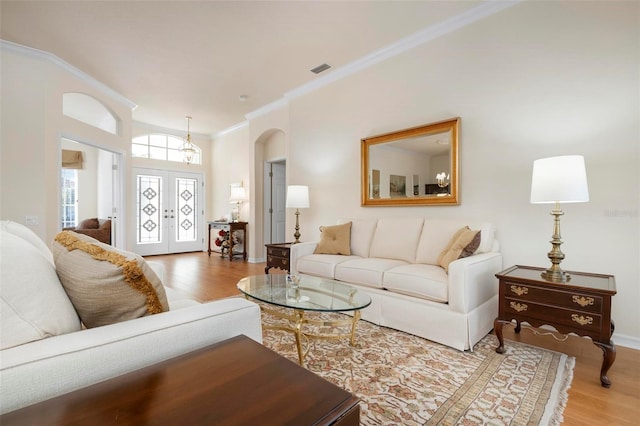 living room featuring hardwood / wood-style flooring, crown molding, and french doors