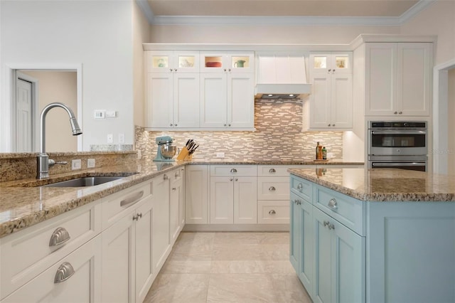 kitchen with white cabinetry, sink, and light stone countertops