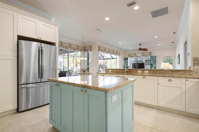 kitchen with white cabinetry, stainless steel refrigerator, and a kitchen island