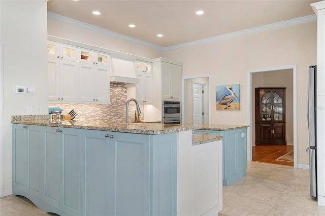 kitchen featuring white cabinets, light stone counters, kitchen peninsula, and premium range hood