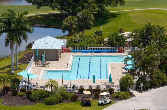 view of pool with a patio area, a yard, and a water view