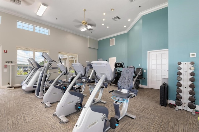 exercise room with carpet flooring, ceiling fan, crown molding, and a high ceiling