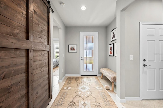 entryway with a barn door and light tile patterned flooring