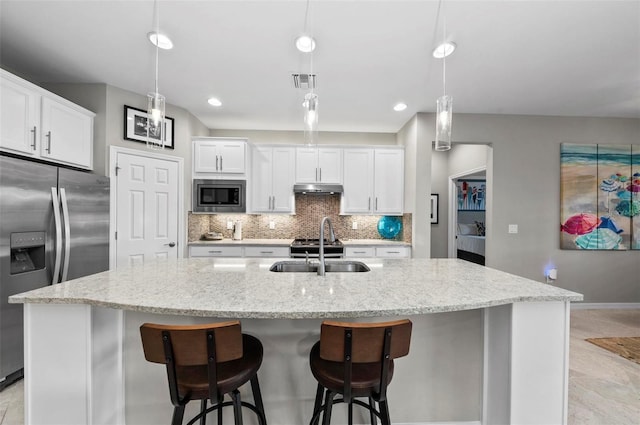 kitchen with white cabinets, an island with sink, stainless steel appliances, and decorative light fixtures