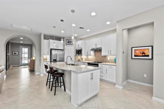 kitchen featuring sink, light stone countertops, an island with sink, white cabinetry, and stainless steel appliances