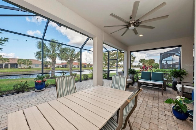 sunroom featuring ceiling fan and a water view