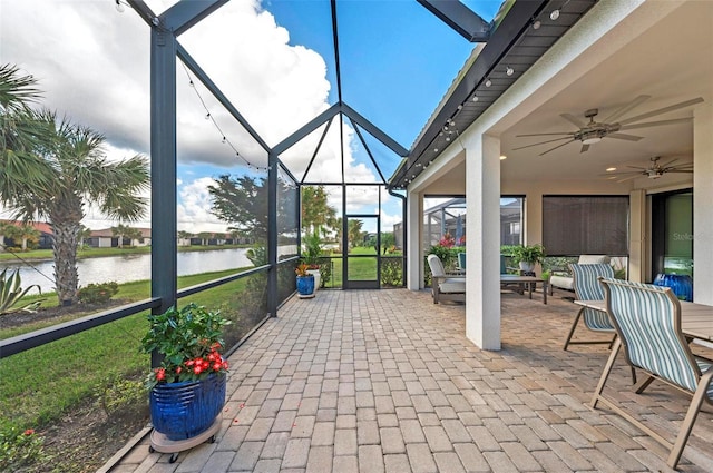 sunroom featuring ceiling fan and a water view