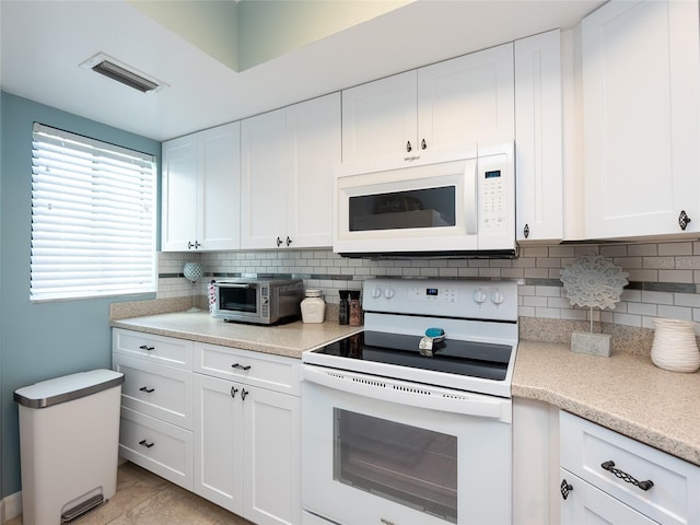 kitchen with decorative backsplash, light tile patterned floors, white appliances, and white cabinetry