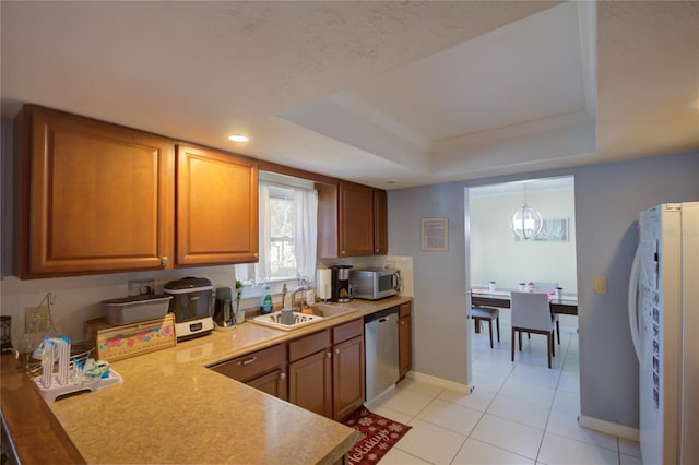 kitchen with sink, hanging light fixtures, stainless steel appliances, a raised ceiling, and light tile patterned floors