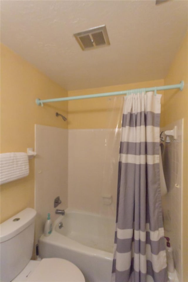 bathroom featuring shower / tub combo and toilet