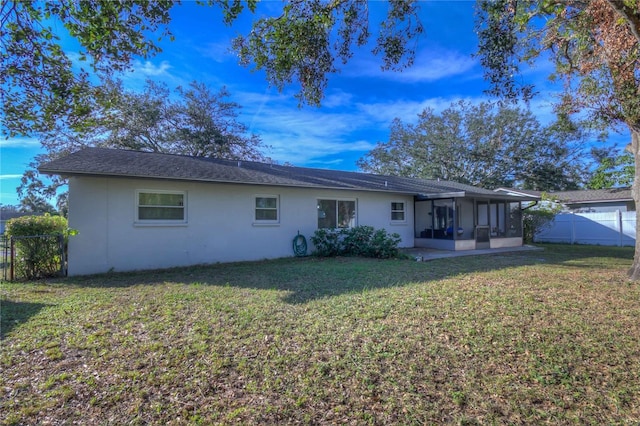 rear view of house featuring a lawn and a sunroom