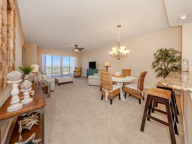 carpeted dining area with ceiling fan with notable chandelier