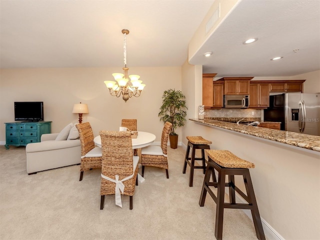 dining space with light carpet and a chandelier