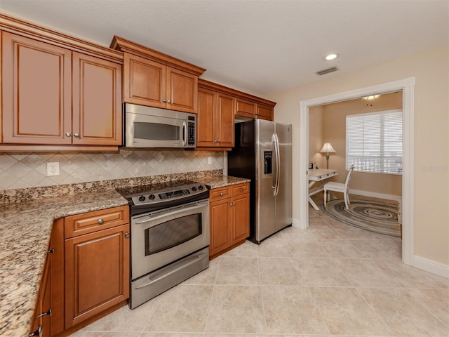 kitchen featuring light stone countertops, stainless steel appliances, light tile patterned floors, and tasteful backsplash