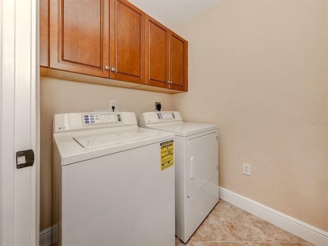 laundry room featuring washing machine and clothes dryer, light tile patterned floors, and cabinets