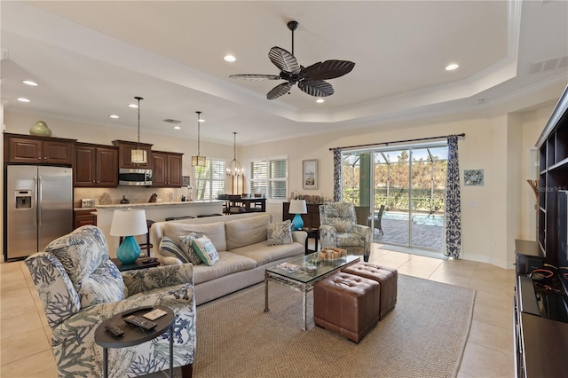 living room with a raised ceiling, ceiling fan, and plenty of natural light